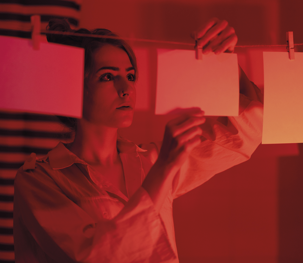 Image of a young woman developing photos in a darkroom